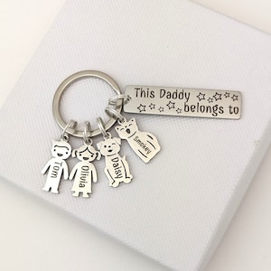 May include: Silver keychain with a tag that reads "This Daddy belongs to" with five stars. The keychain has charms of a boy, a girl, a dog, and a cat. The charms are engraved with the names Tom, Olivia, Daisy, and Smokey.
