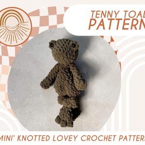 May include: A crochet pattern for a 'Mini' Knotted Lovey Crochet pattern, featuring a brown crocheted toad named Tenny Toad. The pattern is available as a digital download.