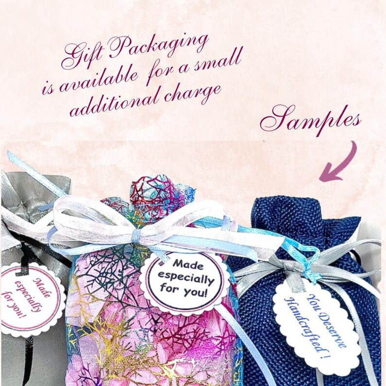 May include: Three small drawstring gift pouches in silver, pink with a gold mesh overlay, and dark blue textured fabric. Each pouch features a white scalloped tag with the text Made especially for you! or You Deserve Handcrafted! and ribbon ties.