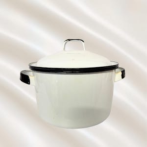 May include: A white enamel stockpot with a matching lid, featuring a black rim around the top edge and the lid. The pot has two side handles with black accents and a small metal handle on the center of the lid, providing a classic kitchen look.