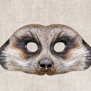 May include: A brown and gray meerkat mask with cutouts for the eyes. The mask is made of felt and has a realistic meerkat face.