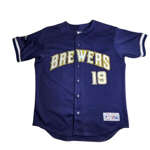May include: Navy blue baseball jersey with the word "BREWERS" in yellow and white lettering across the chest. The number "19" is below the word "BREWERS". The jersey has white stripes on the sleeves.