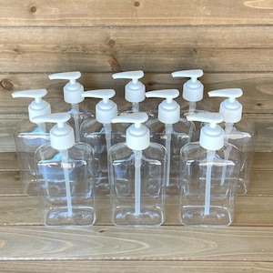 May include: Ten clear plastic bottles with white pump tops. The bottles are arranged in two rows of five. The bottles are all empty.