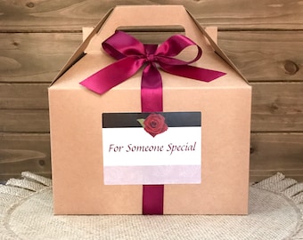 May include: A brown cardboard gift box with a burgundy ribbon and bow. The box has a label that says "For Someone Special" with a red rose graphic.