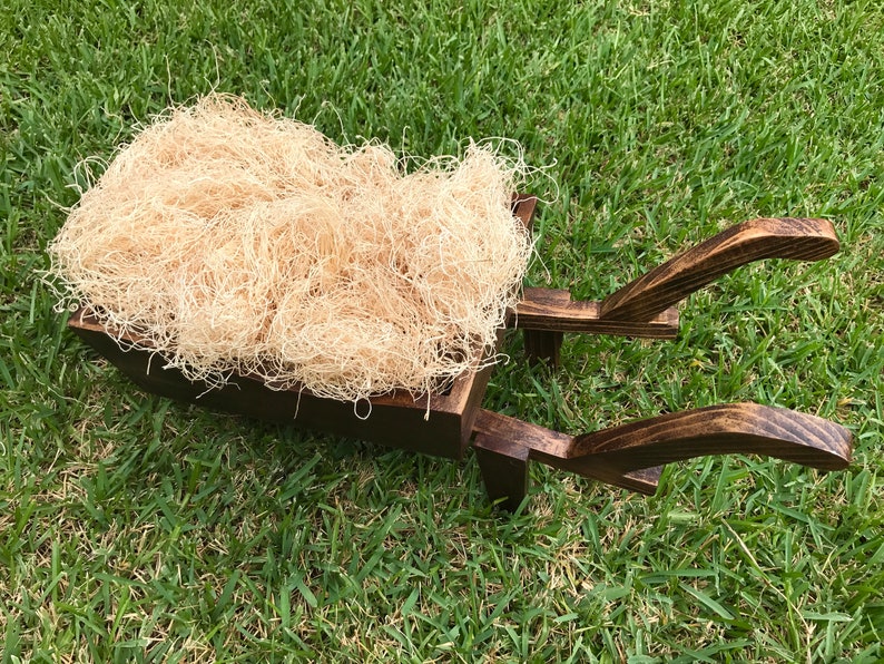 以下が含まれることがあります： 緑の草を背景に、明るい茶色の細断されたフィラーが詰められた、素朴な濃い茶色の木製手押し車。 手押し車は、写真撮影の小道具に最適なクラシックなデザインです。 寸法はcmです。