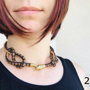 Pu&ograve; includere: Una collana di serpente con perline nere e dorate con un ciondolo a forma di testa di serpente dorata. La collana &egrave; lunga 27 pollici.