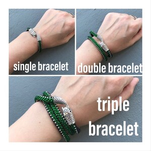 Pu&ograve; includere: Tre braccialetti a forma di serpente verdi con teste di serpente argentate. I braccialetti sono mostrati sul polso di una persona. Il testo "braccialetto singolo", "braccialetto doppio" e "braccialetto triplo" &egrave; mostrato sotto ogni immagine.