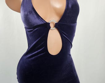 May include: A dark purple velvet halter dress with a keyhole cutout and a rhinestone ring detail. The dress is form-fitting and has a mini length.