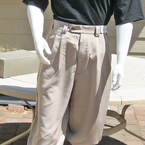 Puede incluir: Maniquí vestido con atuendo de golf. El conjunto incluye un polo negro, pantalones bombachos color caqui, calcetines de rombos y zapatos de golf bicolor. Un boina marrón con un emblema dorado completa el look.