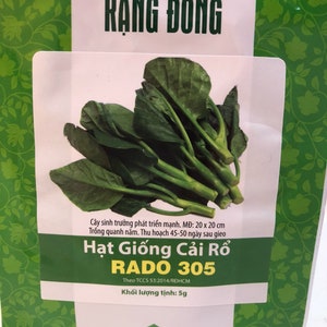 May include: A green and white packet of RADO 305 Chinese Cabbage seeds. The packet features a photo of the vegetable and the text "RẠNG ĐÔNG" and "Hạt Giống Cải Rổ".