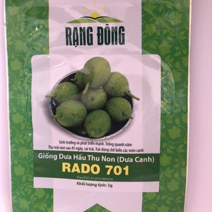 May include: A packet of RADO 701 watermelon seeds. The packet features a green background with a floral pattern and a picture of watermelon. The text on the packet reads "RADO 701" and "Giống Dưa Hấu Thu Non (Dưa Canh)".