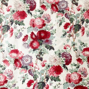 May include: A white fabric with a repeating pattern of red, pink, and purple flowers with green leaves.