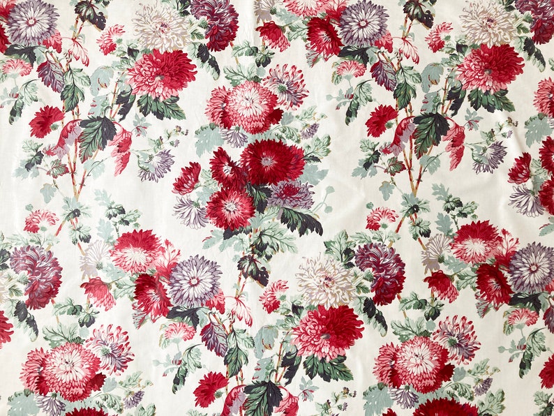 May include: A white fabric with a repeating pattern of red, pink, and purple flowers with green leaves.