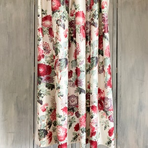 May include: White shower curtain with a floral pattern featuring red, pink, and purple flowers on green stems. The curtain is hung on a metal rod.