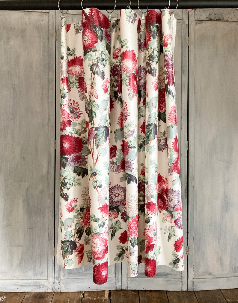 May include: White shower curtain with a floral pattern featuring red, pink, and purple flowers on green stems. The curtain is hung on a metal rod.
