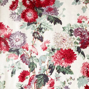 May include: A white fabric with a floral pattern featuring red, pink, and purple flowers with green leaves.