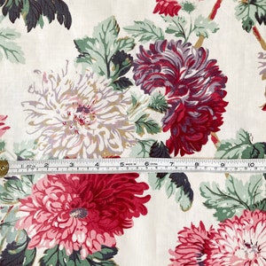 May include: White fabric with a floral print featuring pink, red, and purple flowers. The flowers are stylised and have a vintage look. The fabric is a cotton blend and is perfect for quilting, crafts, and home decor.