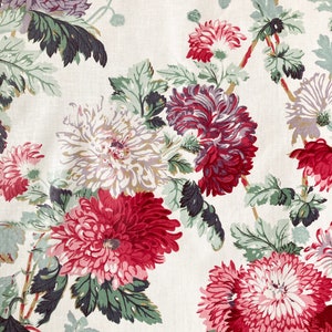 May include: A white fabric with a floral pattern featuring pink, red, and purple flowers with green leaves.
