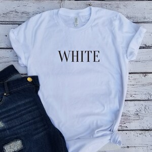 May include: White t-shirt with the word "WHITE" printed in black on the front.