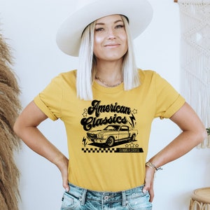 Puede incluir: Una camiseta amarilla con un gr&aacute;fico negro de un coche cl&aacute;sico y el texto "American Classics" en una fuente retro. El gr&aacute;fico tambi&eacute;n incluye estrellas y rayos.