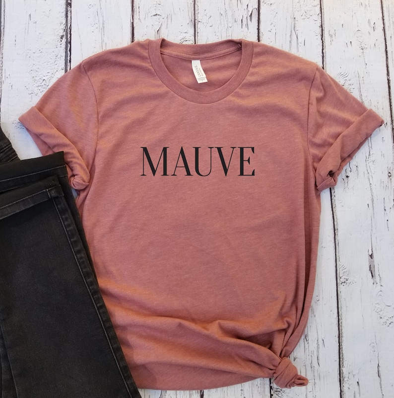 Puede incluir: Camiseta de color malva con la palabra "MAUVE" impresa en negro en la parte delantera.