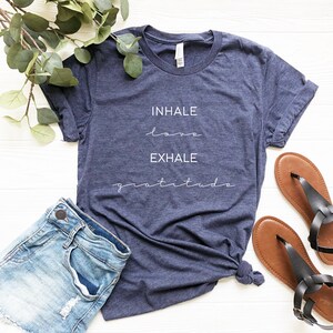 May include: A navy blue t-shirt with the text "INHALE love EXHALE gratitude" printed in white.