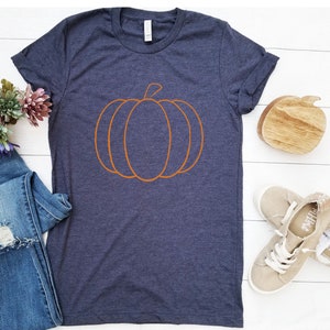 May include: A dark blue t-shirt with an orange outline of a pumpkin.