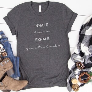 May include: A dark gray t-shirt with the text "INHALE love EXHALE gratitude" printed in white on the front.