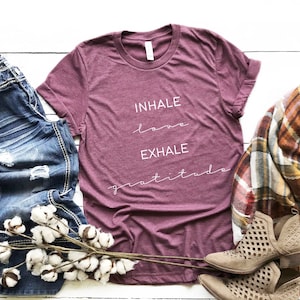 May include: A maroon t-shirt with the text "INHALE love EXHALE gratitude" in white lettering.