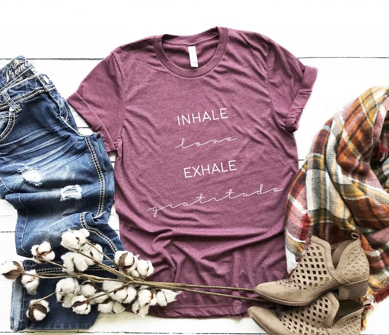 May include: A maroon t-shirt with the text "INHALE love EXHALE gratitude" in white lettering.
