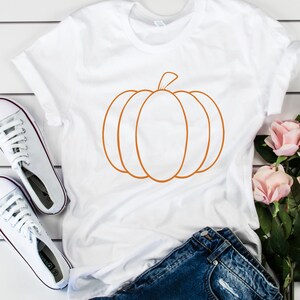 May include: White t-shirt with an orange outline of a pumpkin.