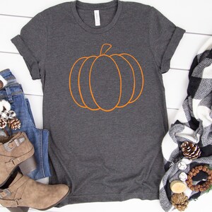 May include: A dark gray t-shirt with an orange outline of a pumpkin on the front.