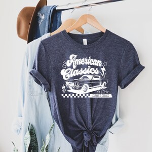 Puede incluir: Una camiseta azul marino con un gr&aacute;fico blanco de un coche cl&aacute;sico y el texto "American Classics" y "Summer Cruise".