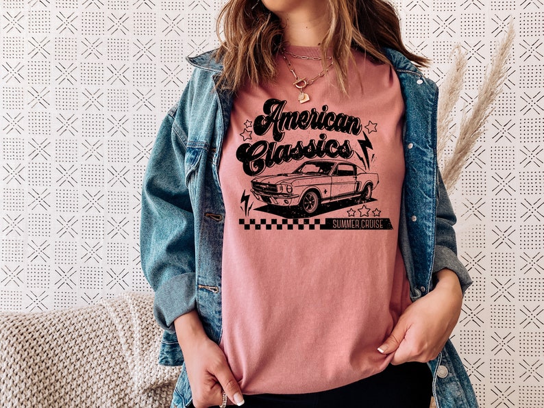 Puede incluir: Una camiseta rosa con un gr&aacute;fico negro de un coche cl&aacute;sico y el texto "American Classics Summer Cruise".
