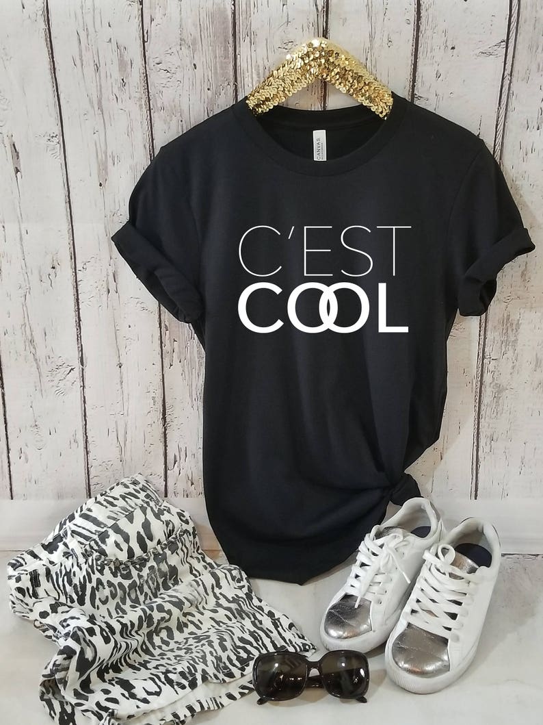 May include: Black t-shirt with white text that reads "C'est Cool" with the "O"s replaced with interlocking circles.