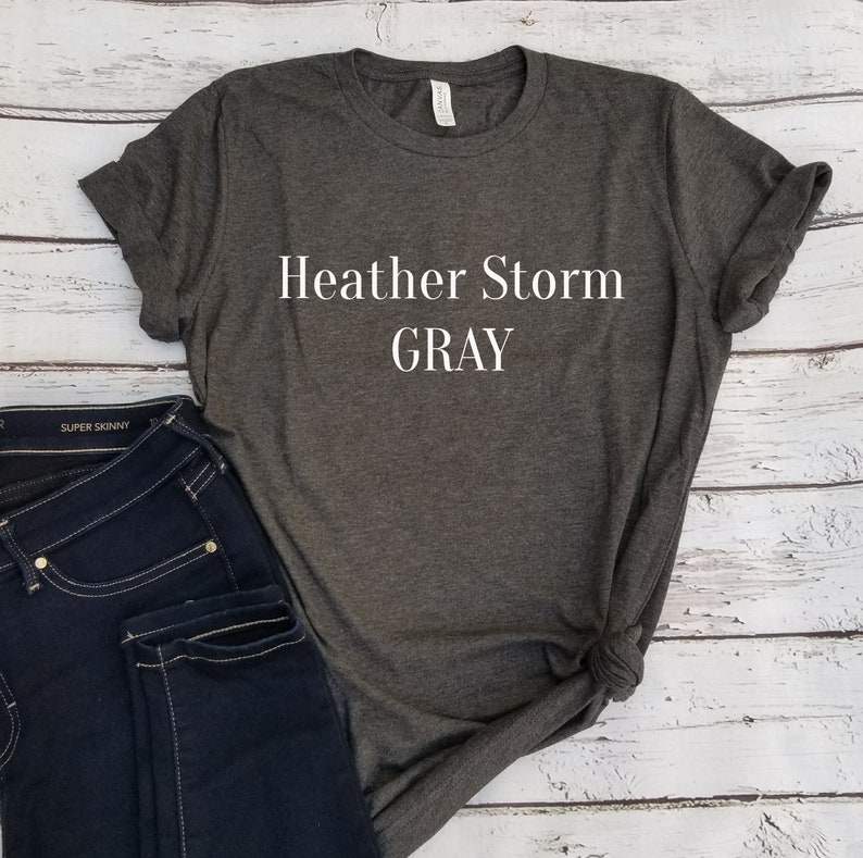 May include: Heather gray t-shirt with the text "Heather Storm GRAY" printed on the front.