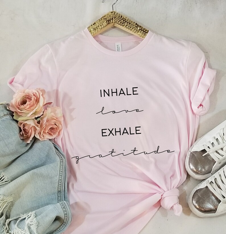 May include: Pink t-shirt with the text "INHALE love EXHALE gratitude" written in black.