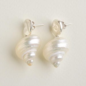 Pu&ograve; includere: Un paio di orecchini con un design a conchiglia a spirale. Gli orecchini hanno un perno d'argento e un colore bianco sporco perlescente. Un accessorio unico.