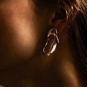 Bold sterling silver statement earrings with fluid organic shape — modern handmade jewelry inspired by ocean forms.
