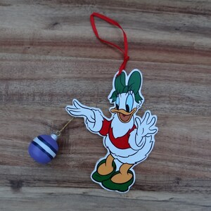 Daisy Duck ornament - Daisy is holding a hanging ball shaped ornament