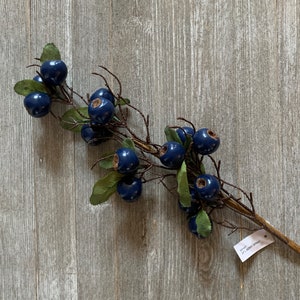 May include: A blue berry spray with green leaves and a brown stem. The spray is 32 inches long and is perfect for adding a touch of nature to your home decor.