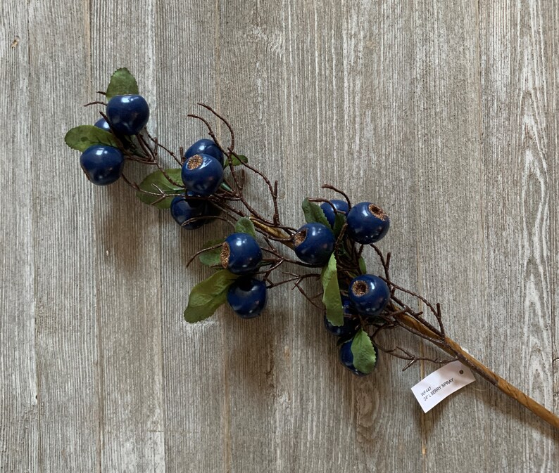 May include: A blue berry spray with green leaves and a brown stem. The spray is 32 inches long and is perfect for adding a touch of nature to your home decor.