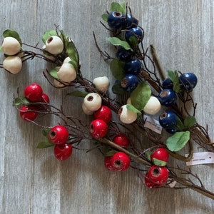 May include: A collection of artificial berry sprigs with red, white, and blue berries. The sprigs are arranged in a bouquet and are ready to be used in a craft project or home decor.
