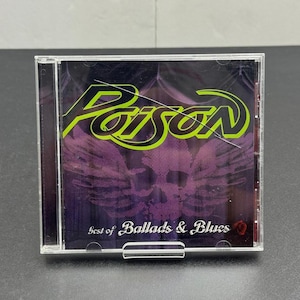 May include: A CD case featuring the album "Best of Ballads & Blues" by Poison. The cover has a purple background with a skull and wings design. The band's name, "Poison", is in bright green lettering.