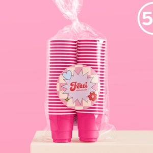 May include: A package of 50 pink and white striped paper cups. The cups are stacked and wrapped in clear plastic. The package has a pink and white label with the text "xo Fetti" and "kafetti.com".