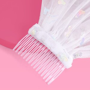 Peut inclure: Voile en tulle blanc avec des paillettes iris&eacute;es et un peigne en plastique transparent. Le voile est attach&eacute; au peigne.