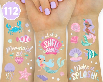 May include: A collection of temporary tattoos featuring colorful sea-themed illustrations including mermaids, a crab, a jellyfish, a starfish, seashells, and fish. The designs include the text "Mermaid at", "Let's SHELL-abrate", and "Make a SPLASH!"