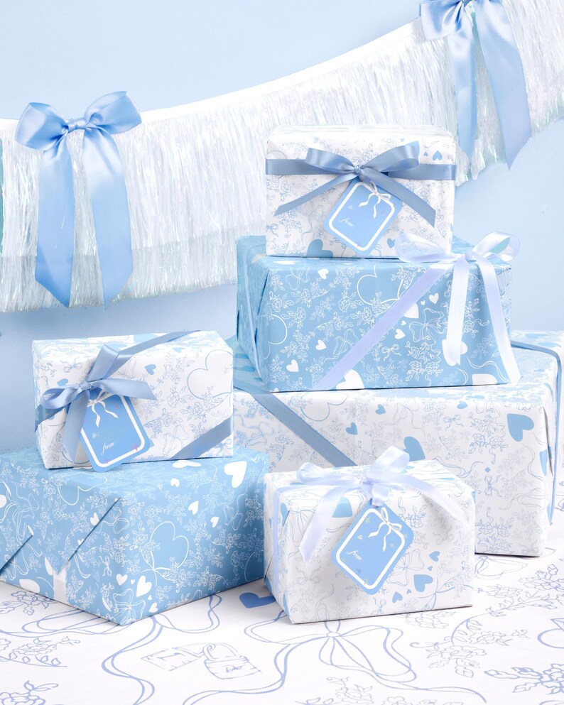 May include: A collection of wrapped presents in blue and white, adorned with ribbons and tags. The wrapping paper displays a pattern of hearts and other designs. The gifts are arranged on a patterned surface, with a blue backdrop.
