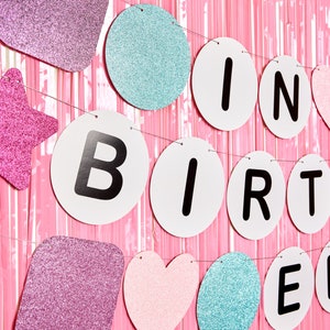 May include: A pink, blue, and white glitter birthday banner with the words "It's Birthday" in black letters.