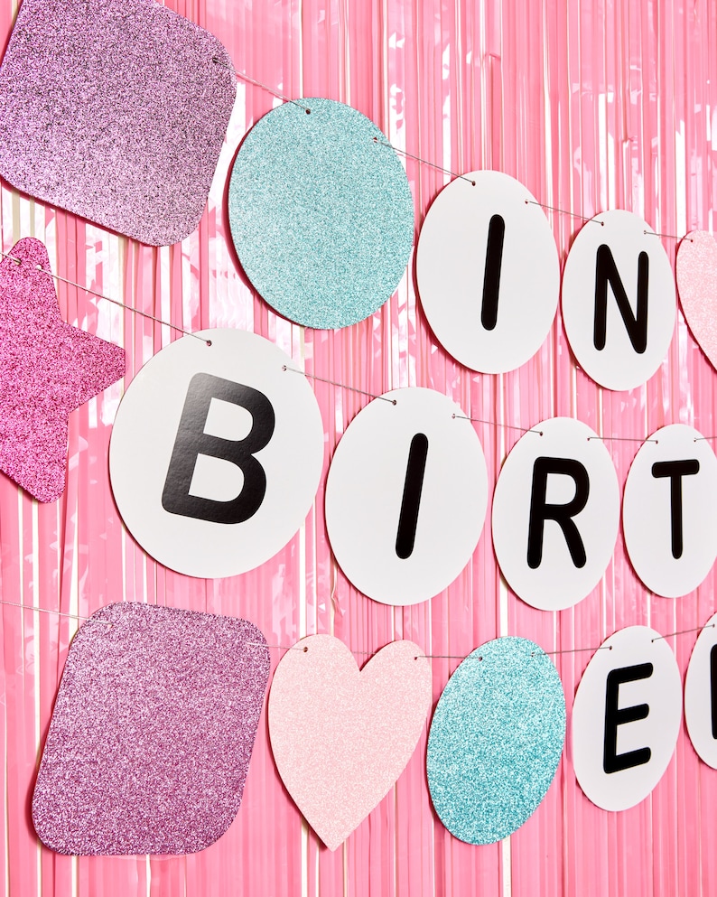 May include: A pink, blue, and white glitter birthday banner with the words "It's Birthday" in black letters.